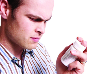 A man is closely examining a medication bottle.