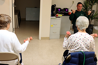 A group of elderly individuals seated in chairs and engaged in light exercises.
