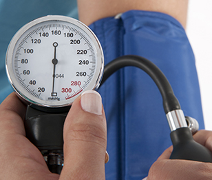 The image shows a close-up of a blood pressure gauge being used on a person's arm.