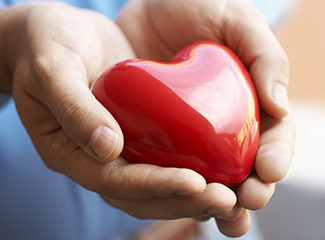 Image of hands holding a bright red heart.