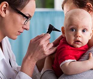 A doctor is examining a baby's ear with an otoscope.
