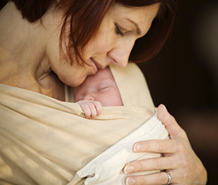 A woman gently embracing a baby in her arms.