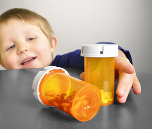 A young child is reaching for prescription medication bottles, highlighting a potential safety hazard.