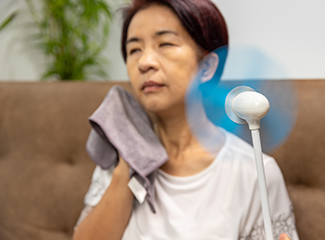 A woman using a fan to enjoy a refreshing breeze on a hot day.