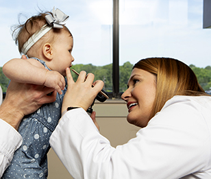 A doctor is examining a baby’s ear with an otoscope.