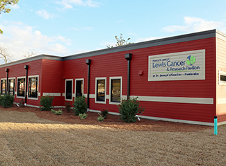 A red building with a sign for the Lewis Cancer & Research Pavilion at St. Joseph’s/Candler in Pembroke.