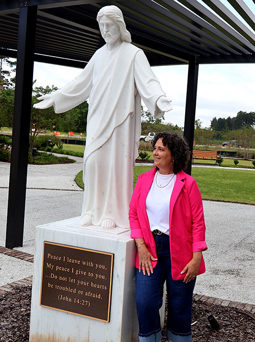 Jennifer Pelletier at the SJ/C Richmond Hill Campus at Heartwood beside the Jesus statute