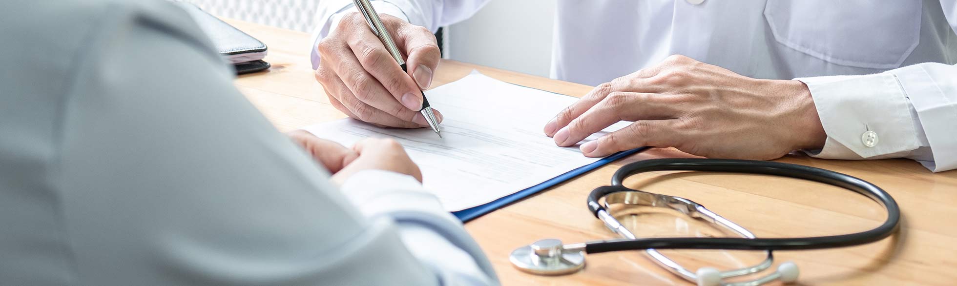 Healthcare provider filling out forms for a patient at his desk