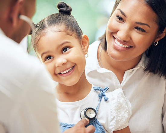 Doctor checking a young child's heart beat as mom holds her