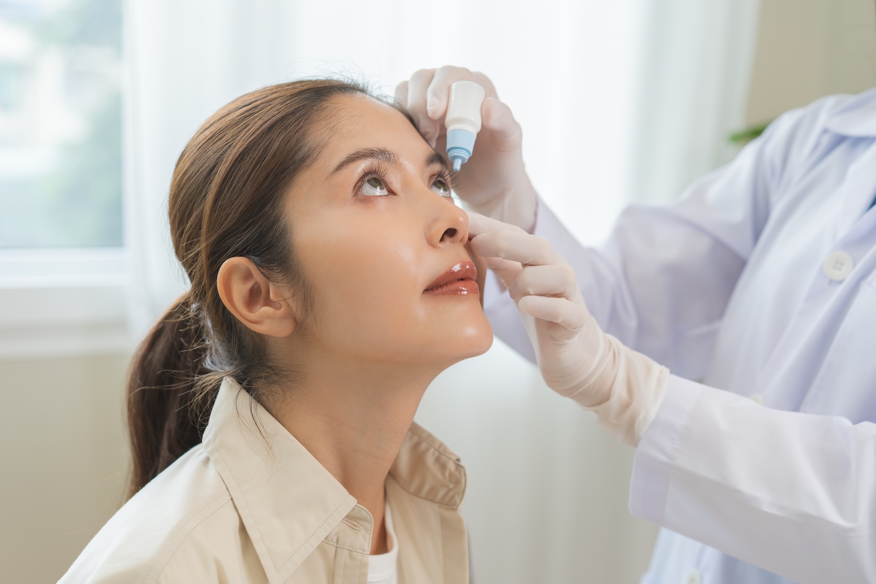 woman in a doctors office receiving eye drops