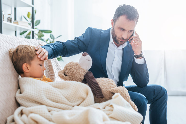 father holding his hand on his son's forehead, checking for a fever