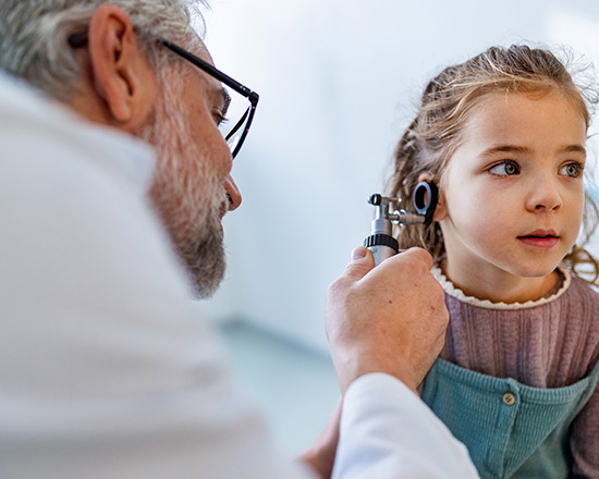 Doctor checking the inside of the ear of a little girl