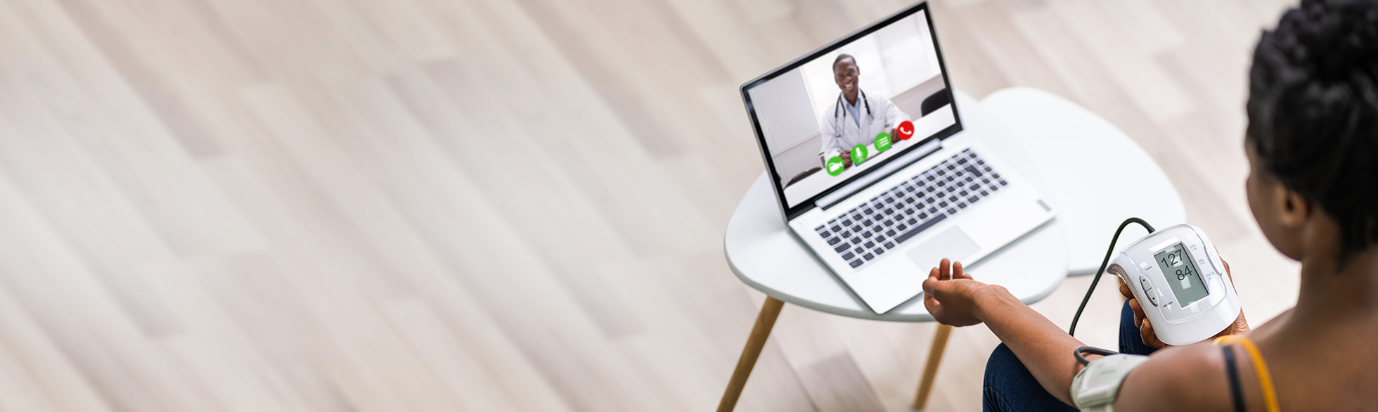 Adult female checking blood pressure while talking to a doctor on her computer